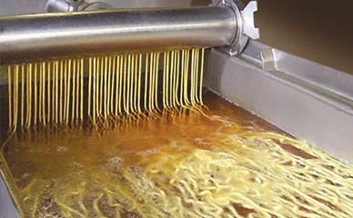 Continuously frying extruded snacks