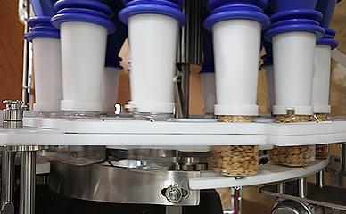 Packaging machine filling containers with nuts